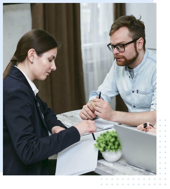 An adviser and a client discussing loan documents at a desk