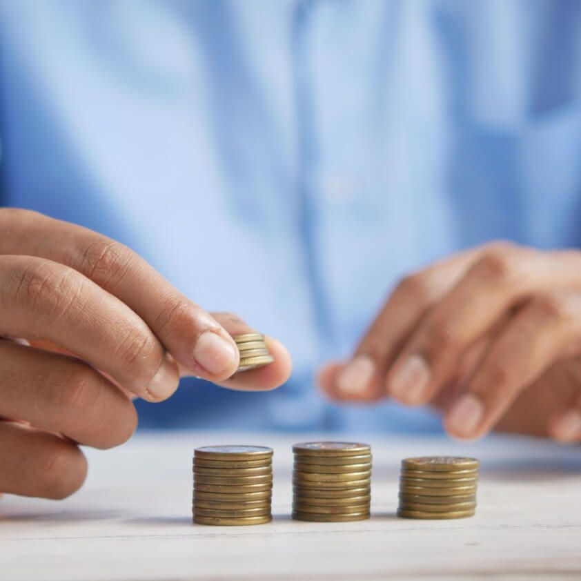 Hand placing coins on growing stacks of coins, representing a debt repayment plan