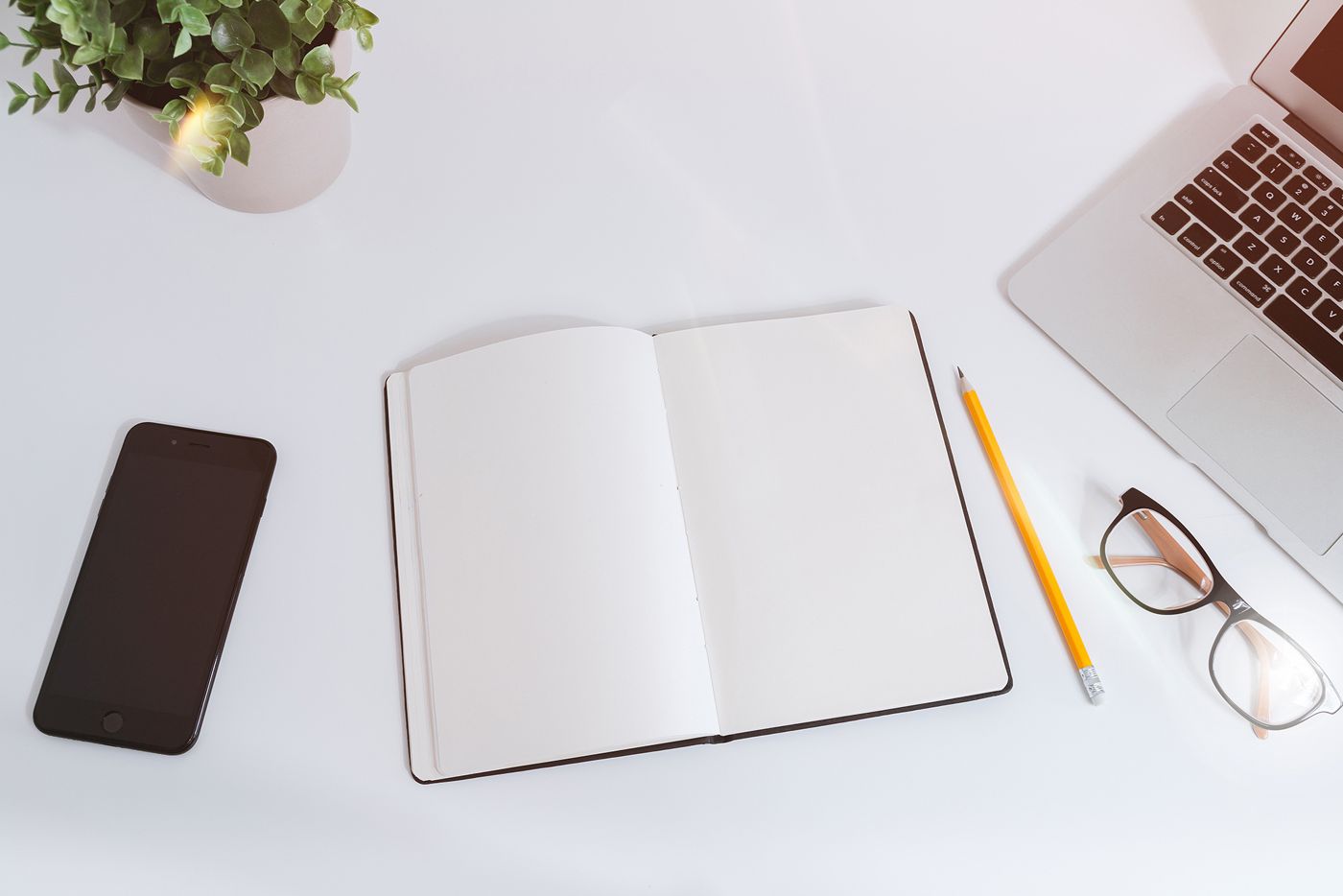 Open notebook, phone, pencil and glasses on a white desk, ready for comparing loan options