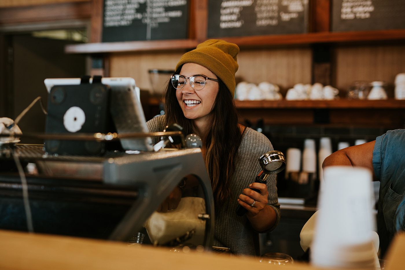 Smiling cafe owner standing behind the counter of a small business